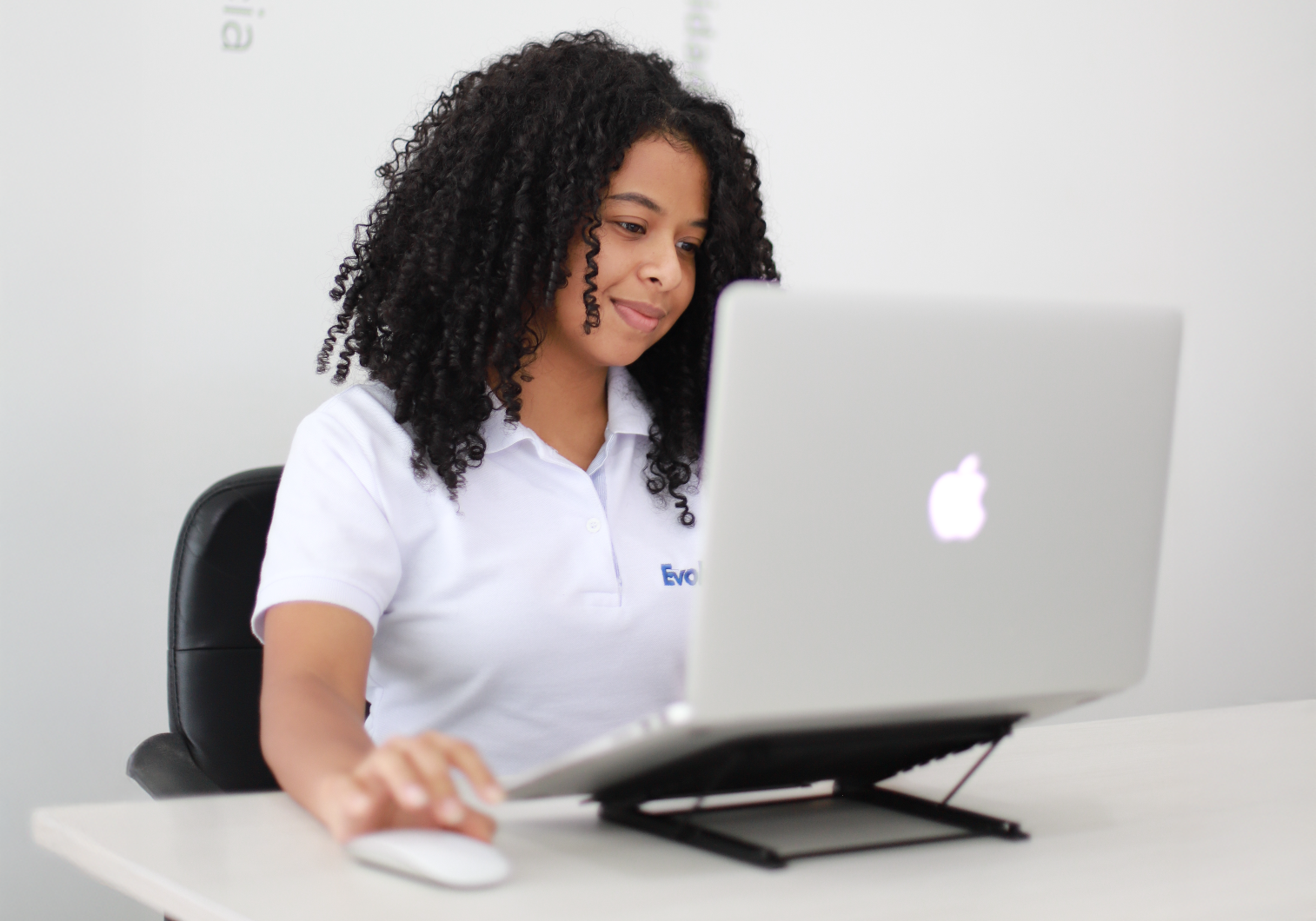 Chica morena sentada frente a un computador sonriendo